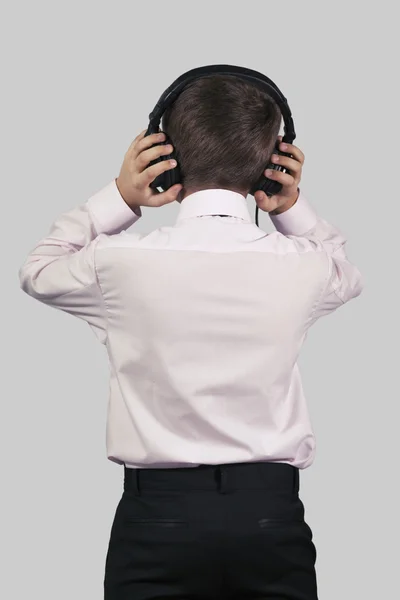 Junge mit Kopfhörern auf grauem Hintergrund mit dem Rücken zur Ansicht — Stockfoto