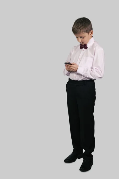 A boy on a gray background dials on your smartphone — Stock Photo, Image