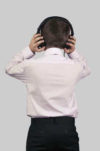 Boy in headphones on a gray background with his back to the view Royalty Free Stock Images