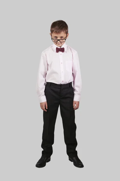 Growth portrait of a boy in a bow tie that looks over his glasse — Stock Photo, Image