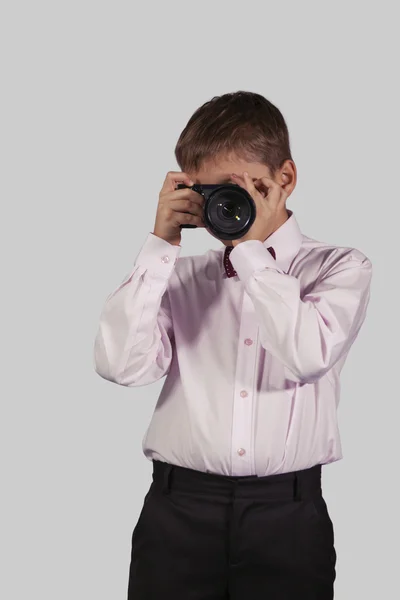 Портрет хлопчика з фотоапаратом на обличчі на сірому — стокове фото