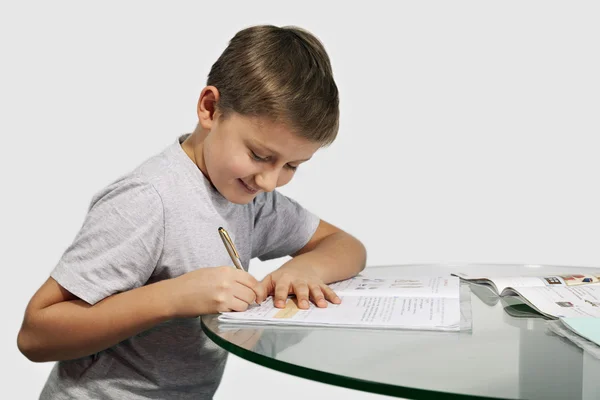 Boy does his homework on a glass table — Stock Photo, Image