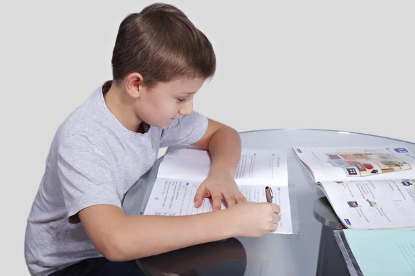 Boy does his homework on a glass table — Stock Photo, Image