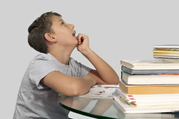 Мальчик сидит в окружении книг и мечтательно смотрит вверх — стоковое фото