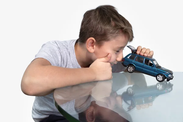 Boy playing with blue car on a glass table — Stock Photo, Image