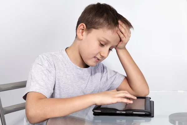 Garçon appuyé sa tête sur la table sur une tablette PC Images De Stock Libres De Droits