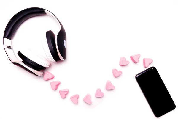 白い背景にスマートフォンを持つ黒と白のヘッドフォン マシュマロの心の形のワイヤ あなたの心に耳を傾ける バレンタインデー コピースペース — ストック写真