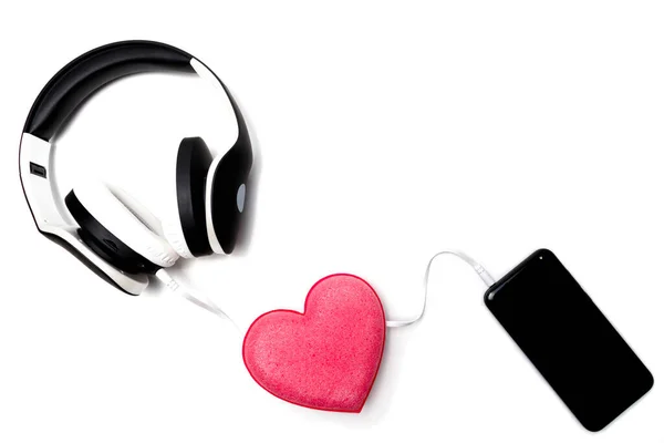 白い背景にスマートフォンと黒白のヘッドフォン ワイヤの真ん中に心の形で愛のシンボル あなたの心に耳を傾ける バレンタインデー スペースのコピー — ストック写真