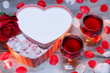 Sevgililer günün kutlu olsun. Kalp şeklinde bir hediye kutusu ve iki bardak kırmızı şarap, misket masasında gül yaprakları var. Kutuda lokum var. Uzayı kopyala Düz yatıyordu.