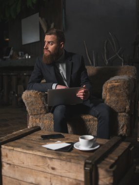 Neşeli genç adam bir dizüstü bilgisayar kullanarak