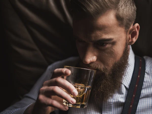 Un homme d'affaires barbu joyeux boit du whisky cher — Photo