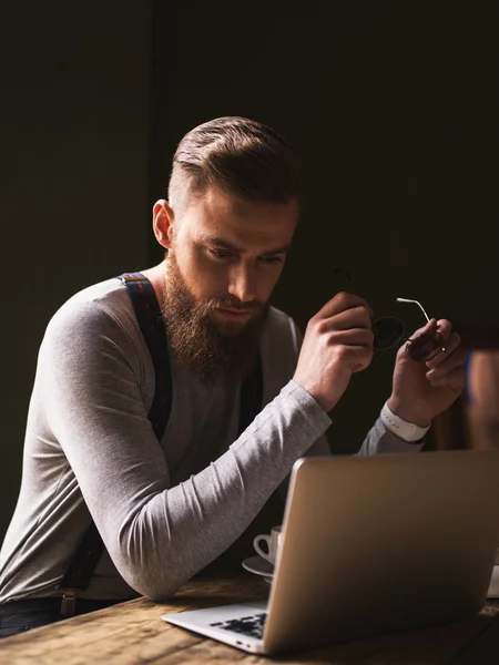 Веселый бородатый парень работает с ноутбуком — стоковое фото