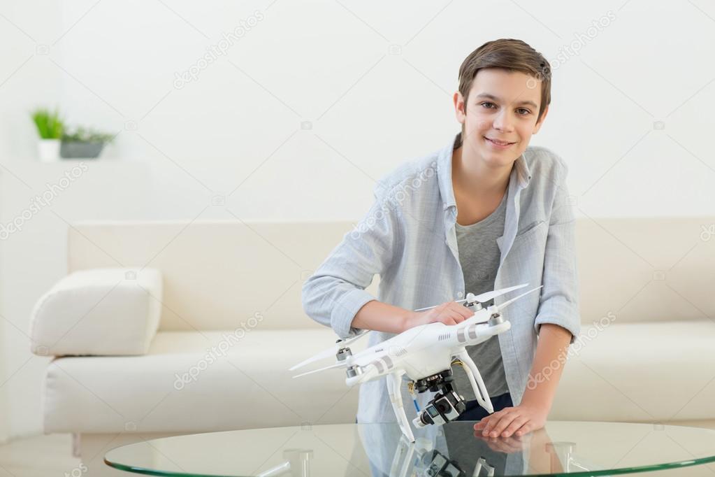 Cheerful male kid is playing with quadrocopter