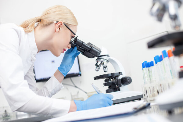 Attractive female laboratory assistant is noting findings