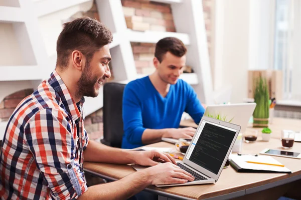 Giovani lavoratori attraenti utilizzano un notebook — Foto Stock