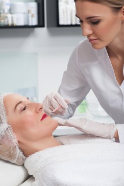 Profesyonel genç kozmetolojist hastasını tedavi ediyor.