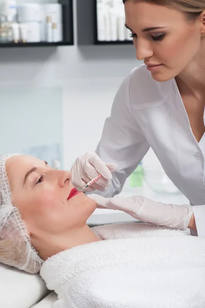 Professional young cosmetologist is treating her patient — Stock Photo, Image