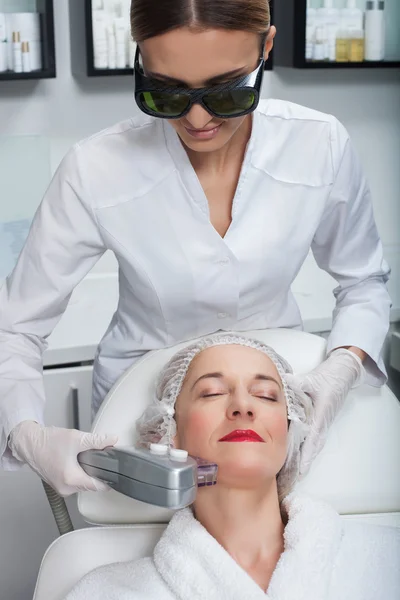 Professional young cosmetician is undergoing laser therapy — Stock Photo, Image