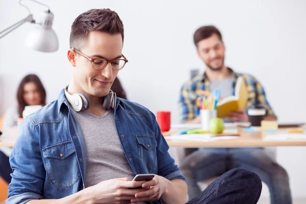 Cheerful young guy is playing with smartphone — Stock Photo, Image