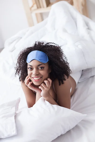 Ganska afrikansk flicka är avkopplande i sängkläder — Stockfoto