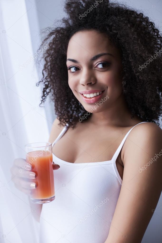 La atractiva mujer mulata sonríe está bebiendo leche cerca de la