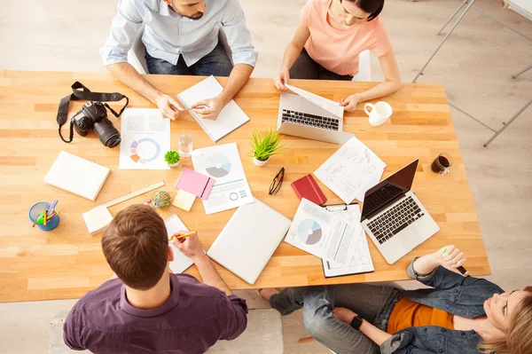 Cuatro jóvenes colegas hablan de trabajo — Foto de Stock