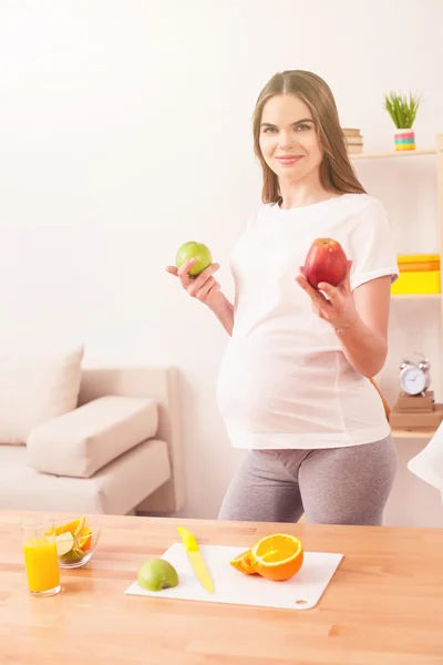 Beautiful pregnant woman is cooking in kitchen — Stock Photo, Image