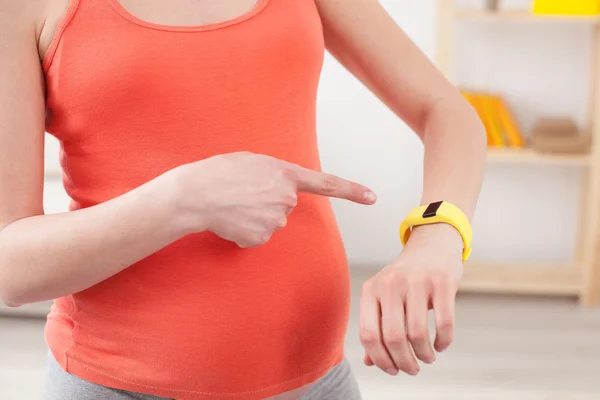 Enchantée femme enceinte vérifie l'heure — Photo