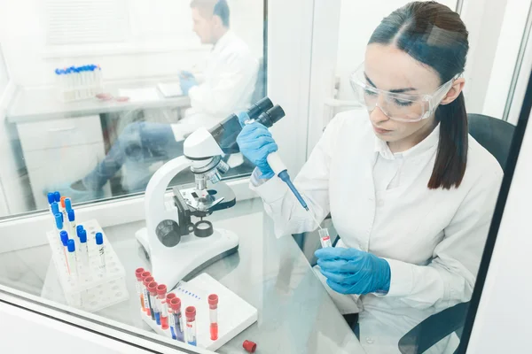 Científicos jóvenes y hábiles examinando virus en laboratorio — Foto de Stock