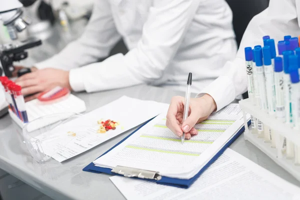 Alegre dois cientistas estão analisando tubos de vidro — Fotografia de Stock