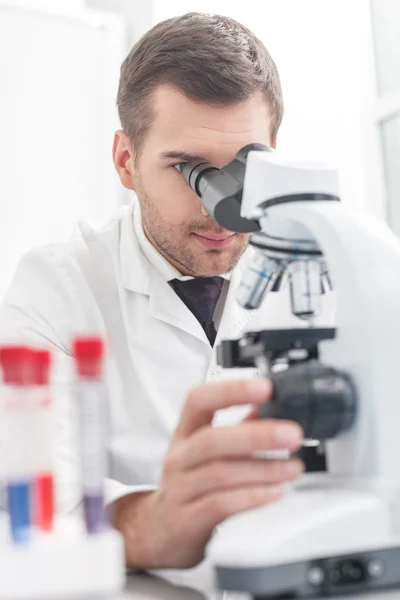 Científico joven hábil está analizando la muestra en el laboratorio — Foto de Stock
