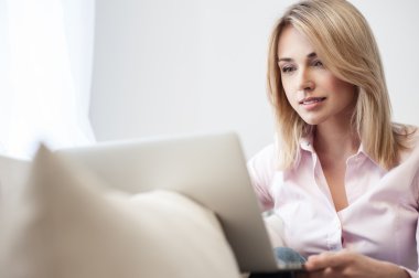 Neşeli sarışın kız bir bilgisayarda yazıyor