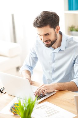 Yakışıklı genç işadamı bilgisayarda yazıyor