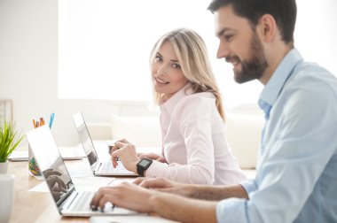 Neşeli genç iş arkadaşları modern dizüstü bilgisayarlar kullanıyor