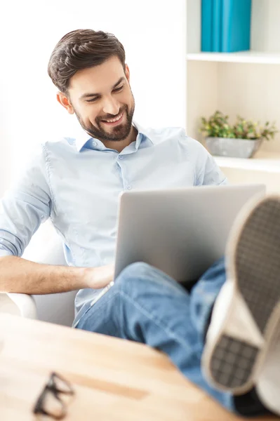 Empresário atraente está trabalhando no laptop com alegria — Fotografia de Stock