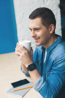 Çekici genç adam sıcak içecek içiyor