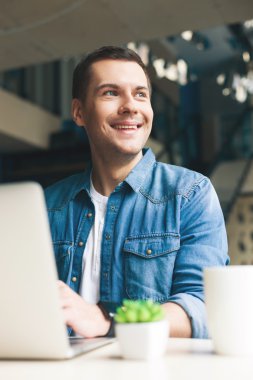 Çekici genç adam bilgisayar üzerinde çalışıyor