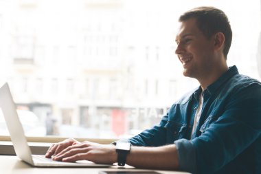 Çekici genç adam dizüstü bilgisayar üzerinde çalışıyor