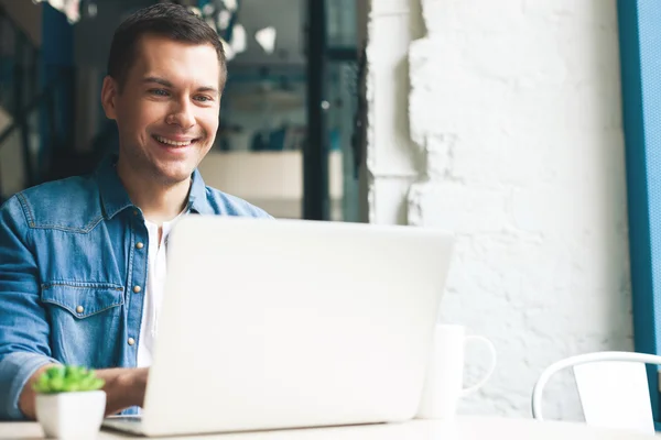 Schöner junger Mann benutzt einen Computer — Stockfoto