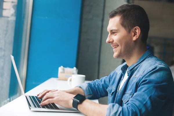 Çekici genç adam bilgisayar üzerinde çalışıyor