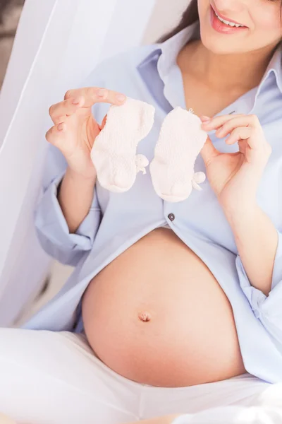 Ganska blivande Mamma visar små kläder — Stockfoto