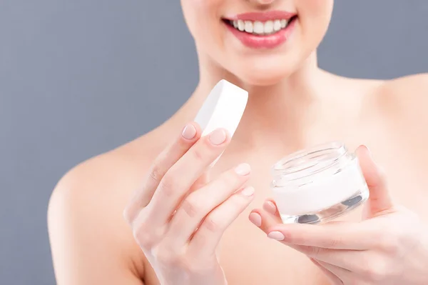 Cheerful young woman is showing cosmetic product — Stock Photo, Image