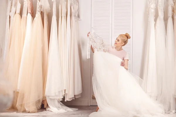 Attractive young woman is selecting bridal gown — Stock Photo, Image