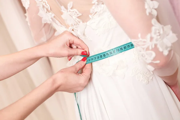 Искусный дизайнер примеряет свадебное платье к девушке — стоковое фото