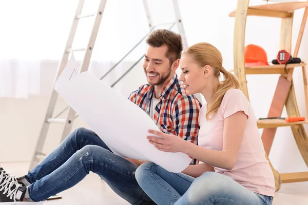 Man och kvinna tittar på deras hus plan — Stockfoto