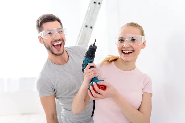 Sorrindo menina holdinhg broca ao lado do cara — Fotografia de Stock