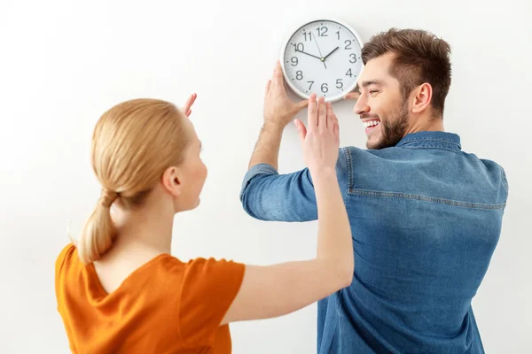 Young couple hanging wall clock — 图库照片