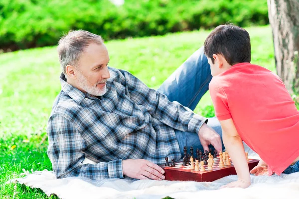 Веселий зрілий чоловік і його онук грають в шахи — стокове фото