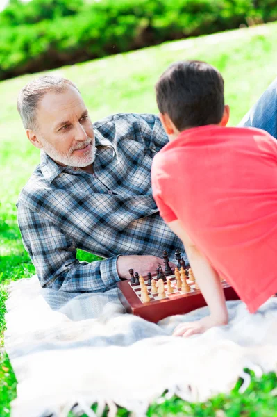熟練した成熟したチェスプレーヤーは、彼の孫を教えています — ストック写真