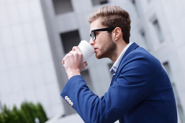 Aantrekkelijke jonge zakenman geniet van warme drank — Stockfoto